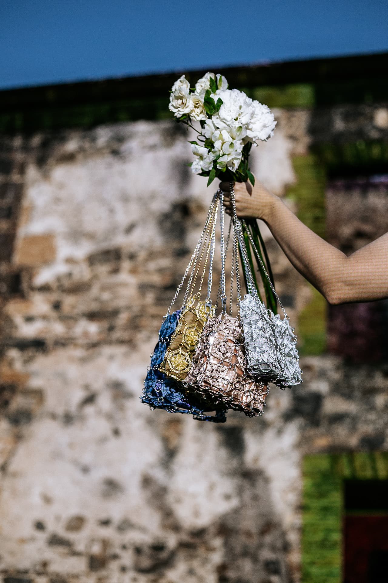 A handful of OCCHI FILO bags held with white flowers