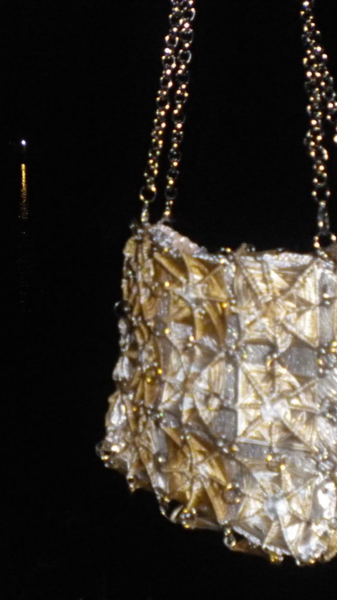 Gold OCCHI FILO bag catching light at night